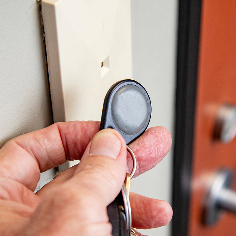 Person using an access control key fob on a card reader to open a door