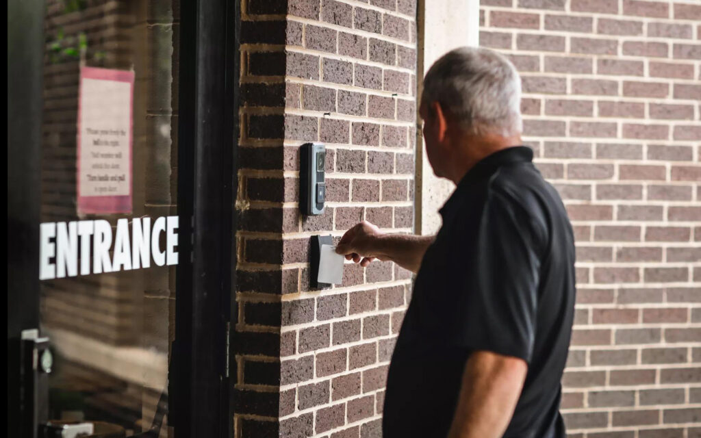 Person using access control key card on card reader to enter building